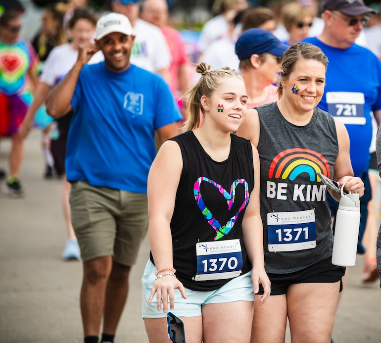 Friends smile while walking in Pride 5K