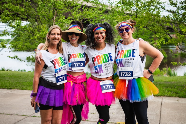 A team wearing matching tutus and Pride 5K T-shirts from The Project of the Quad Cities