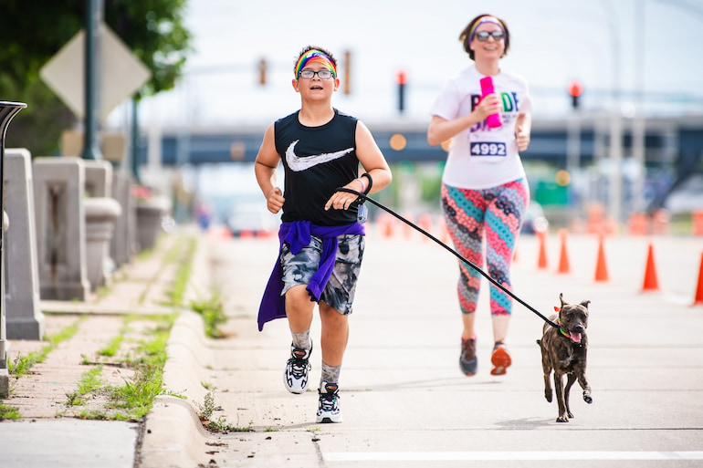 A young boy runs with his dog during the Pride 5K June 15